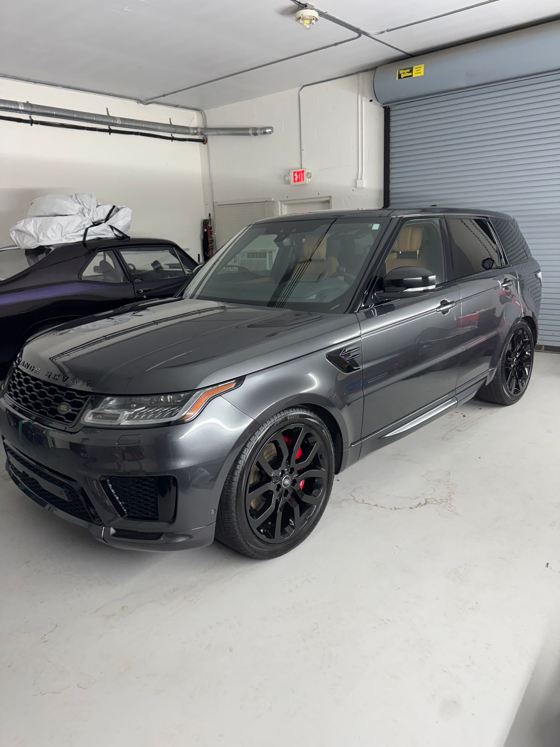 Gray Range Rover in a bright garage, angled front view with black wheels.