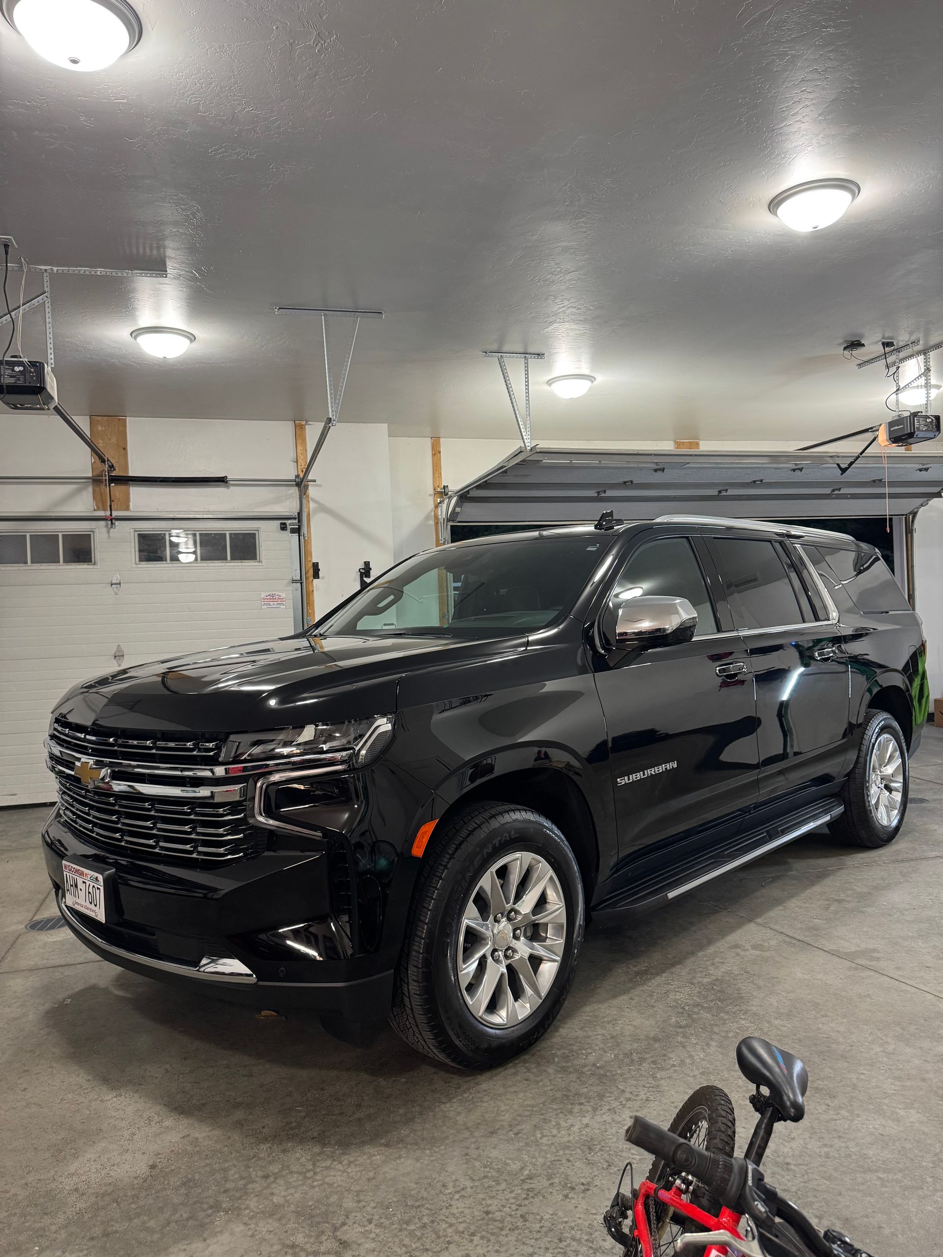 Black SUV parked in a garage with a bicycle in the foreground.