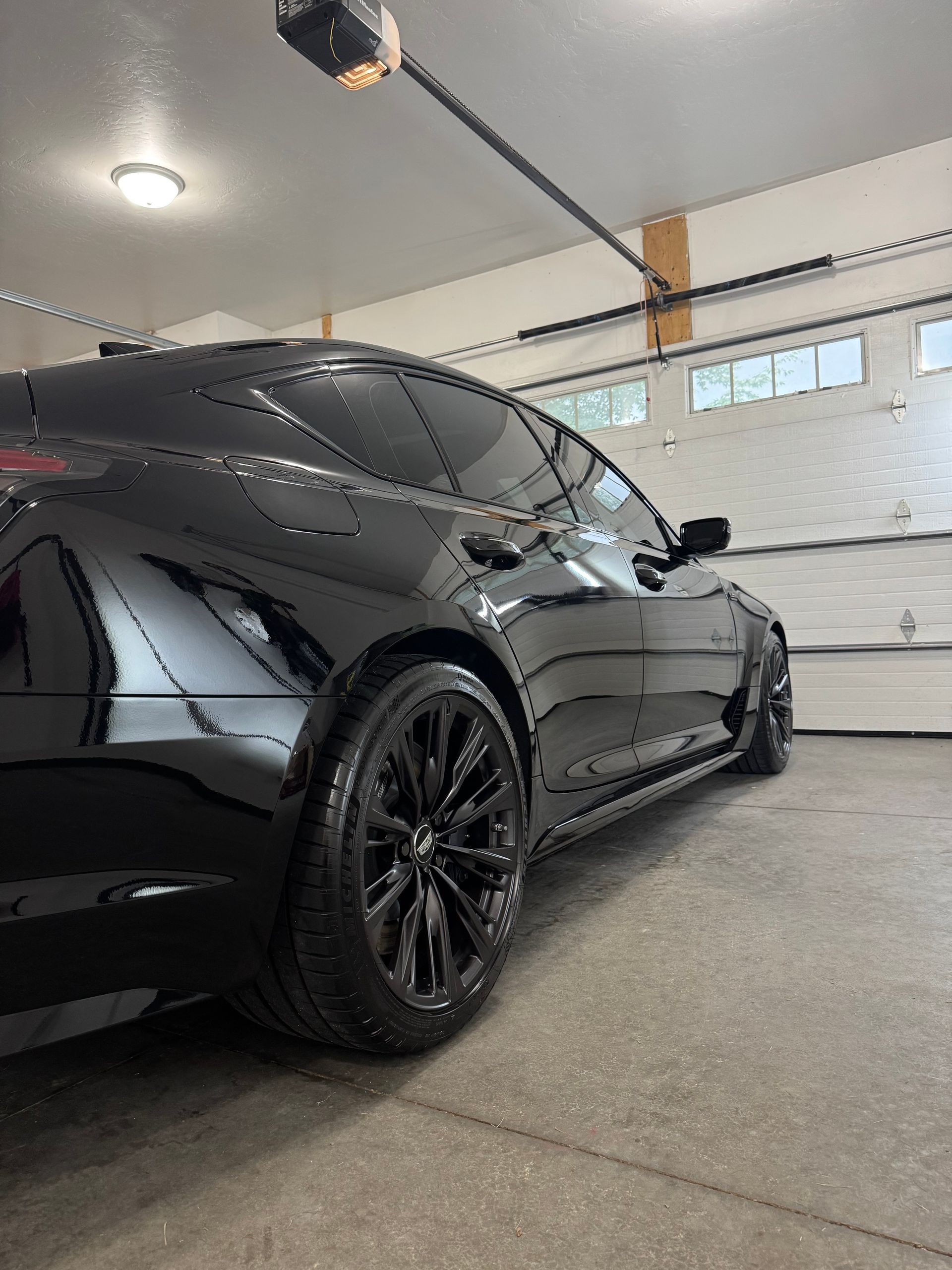 Black sports coupe parked in a garage, seen from the rear side.