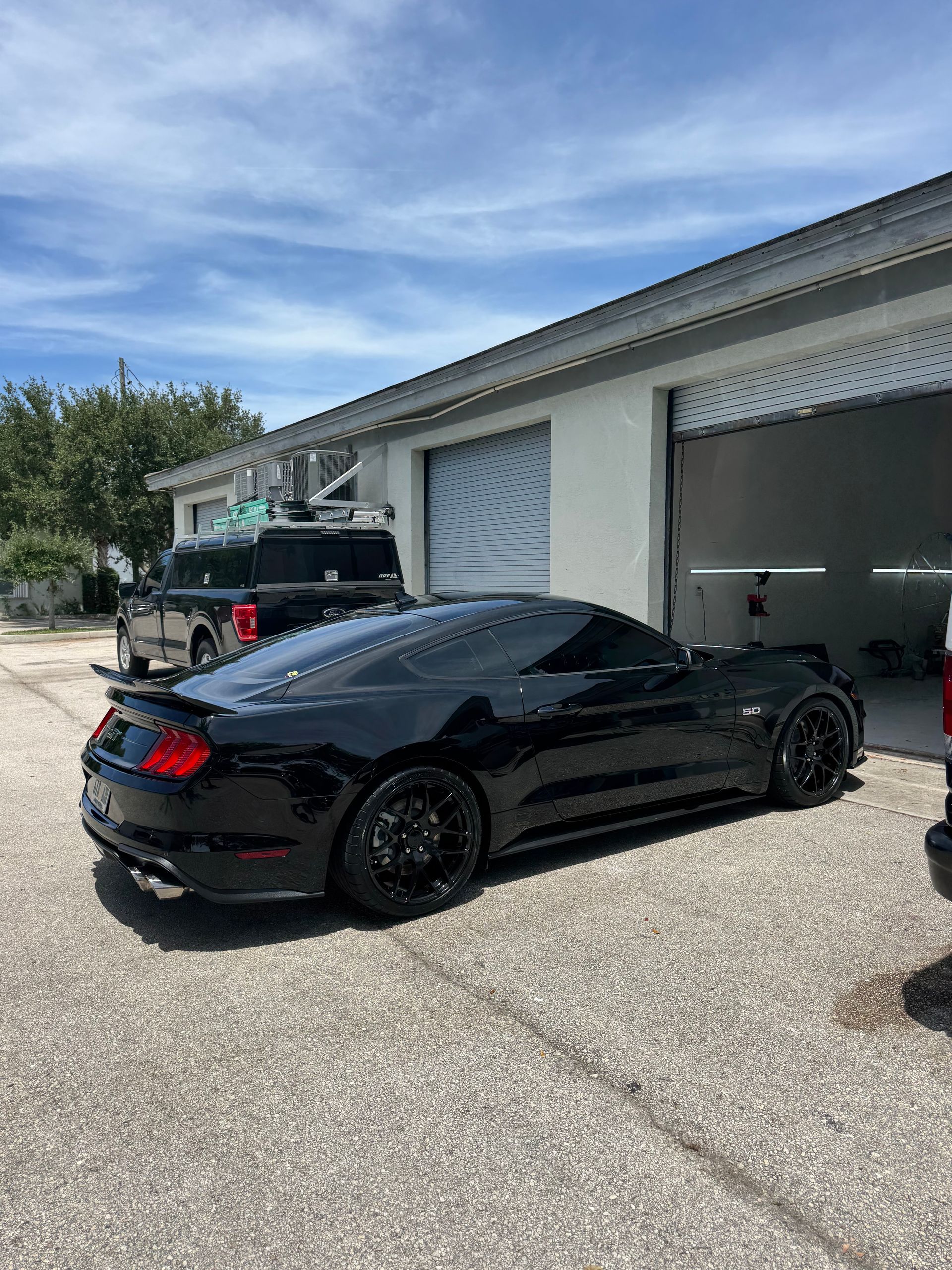 Black sports coupe parked outside a garage in a sunny driveway