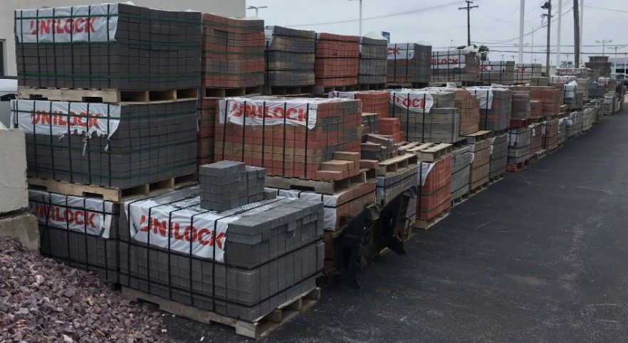 multiple stacks of landscaping pavers and bricks on wooden pallets in an outdoor supply yard. multiple stacks of landscaping pavers and bricks on wooden pallets in an outdoor supply yard.