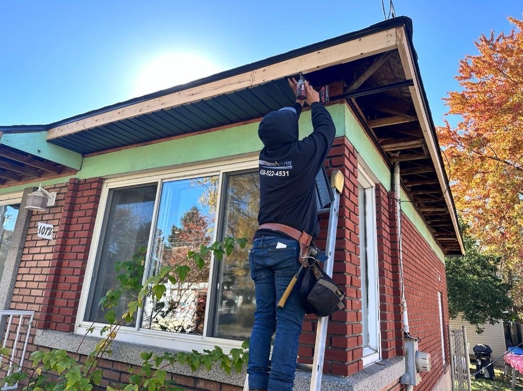 Un homme est debout sur une échelle et travaille sur le toit d'une maison.
