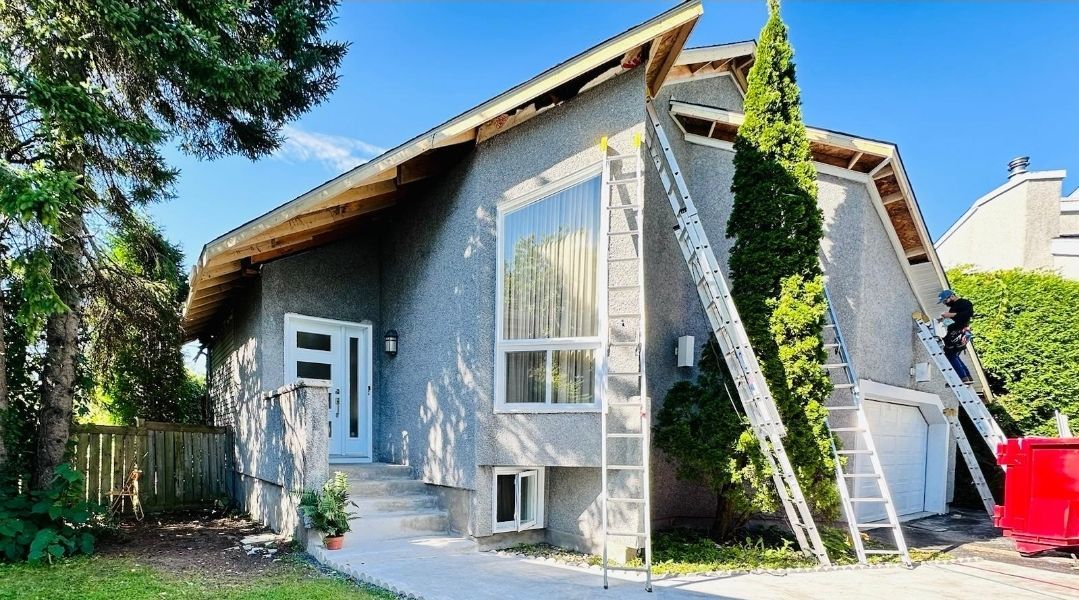 Un homme peint le côté d'une maison avec une échelle.