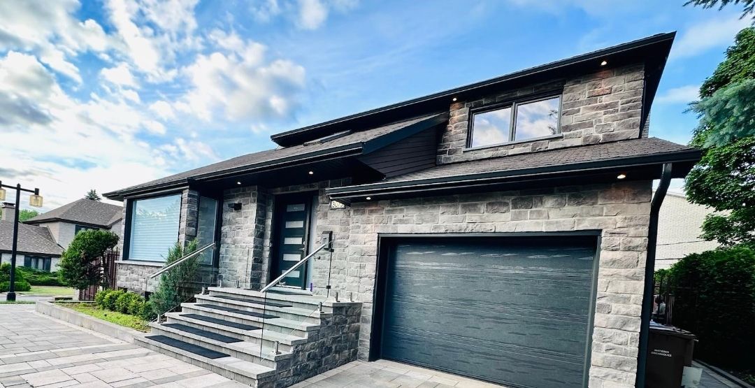 Une grande maison en briques avec un garage et des escaliers devant.