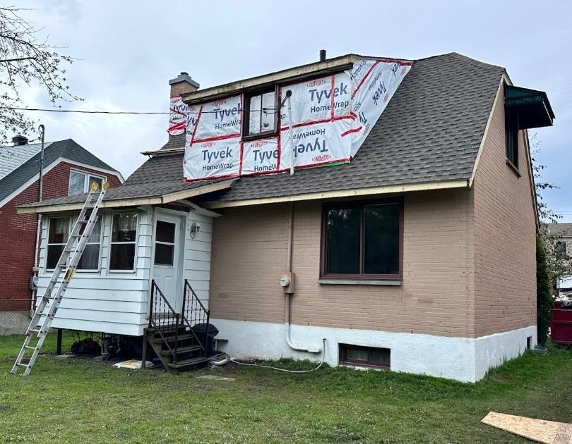 Une maison avec une échelle sur le côté est en cours de rénovation.