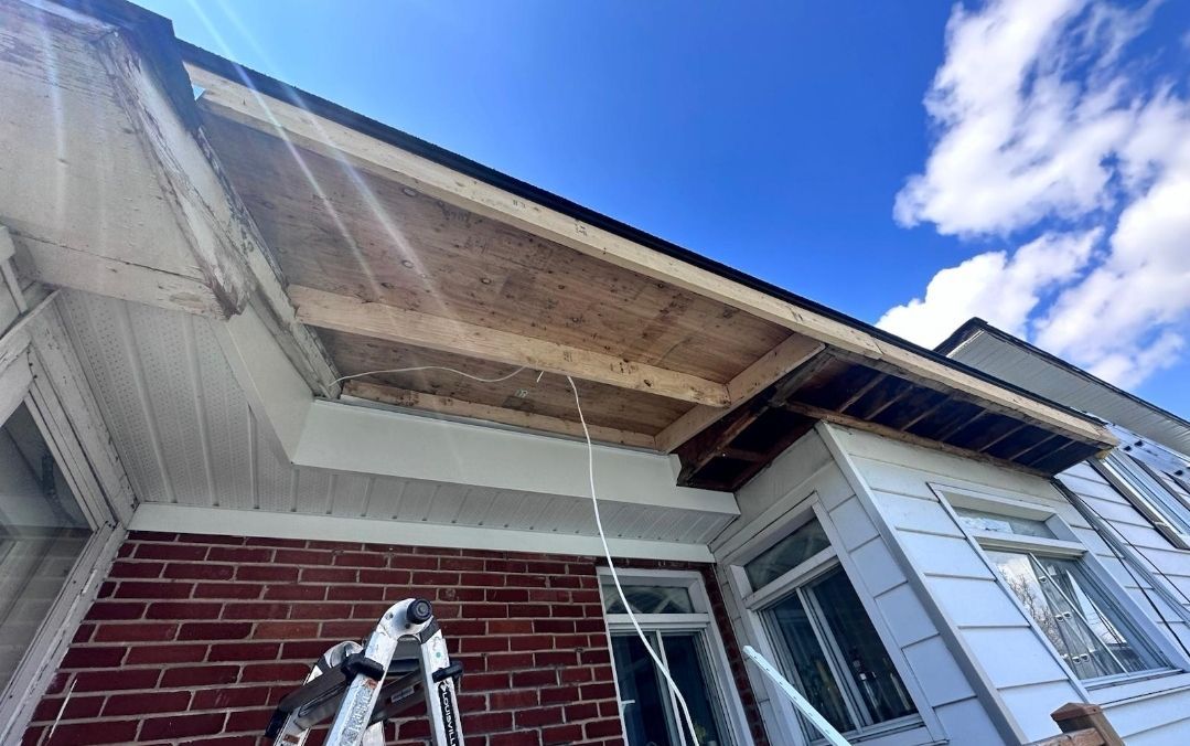 Une personne travaille sur le toit d'une maison en briques.