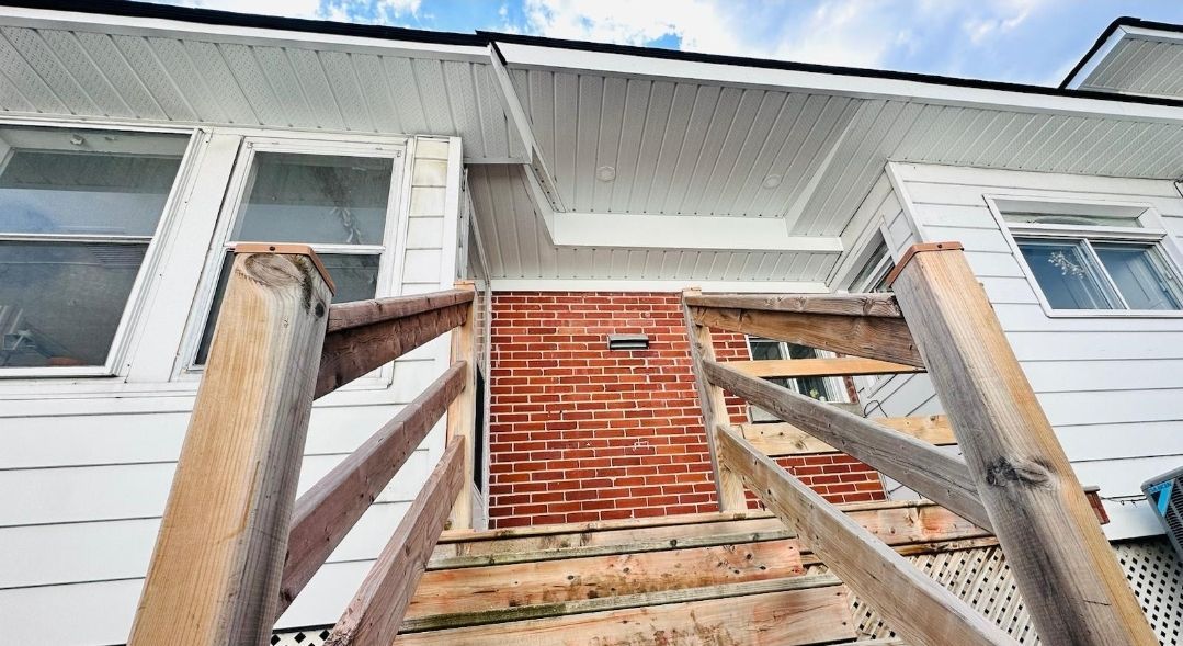 Une maison est en cours de rénovation avec des escaliers en bois et un mur en briques.