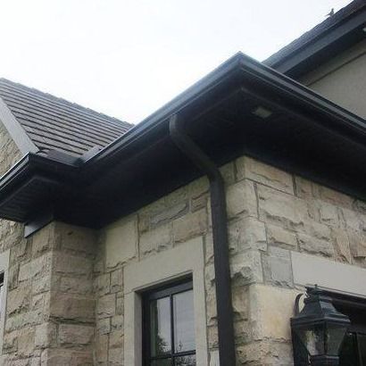 Une maison avec une gouttière noire sur le côté.