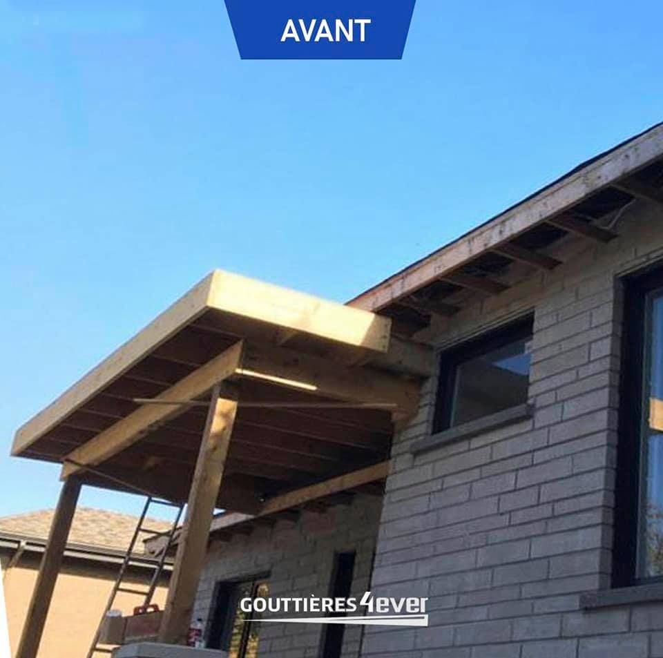 Une maison en briques avec un toit en bois et un panneau bleu indiquant avant
