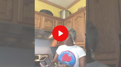 Person in a white T-shirt standing in a kitchen, with a red play button overlay.