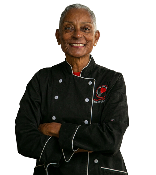 Smiling chef in a black uniform with red accents, arms crossed against a white background