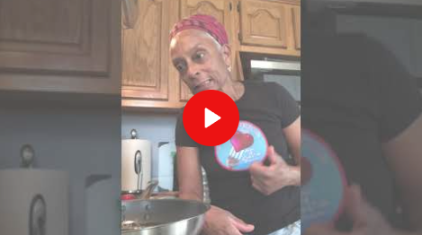 Person in a kitchen holding a pot, with a red play button overlay on the image.