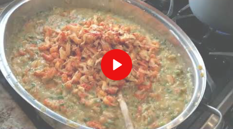 Pan of simmering rice and vegetables with a wooden spoon on a stovetop