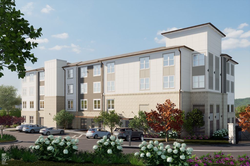 Multi-story apartment building with cars parked in front, trees, and shrubs.