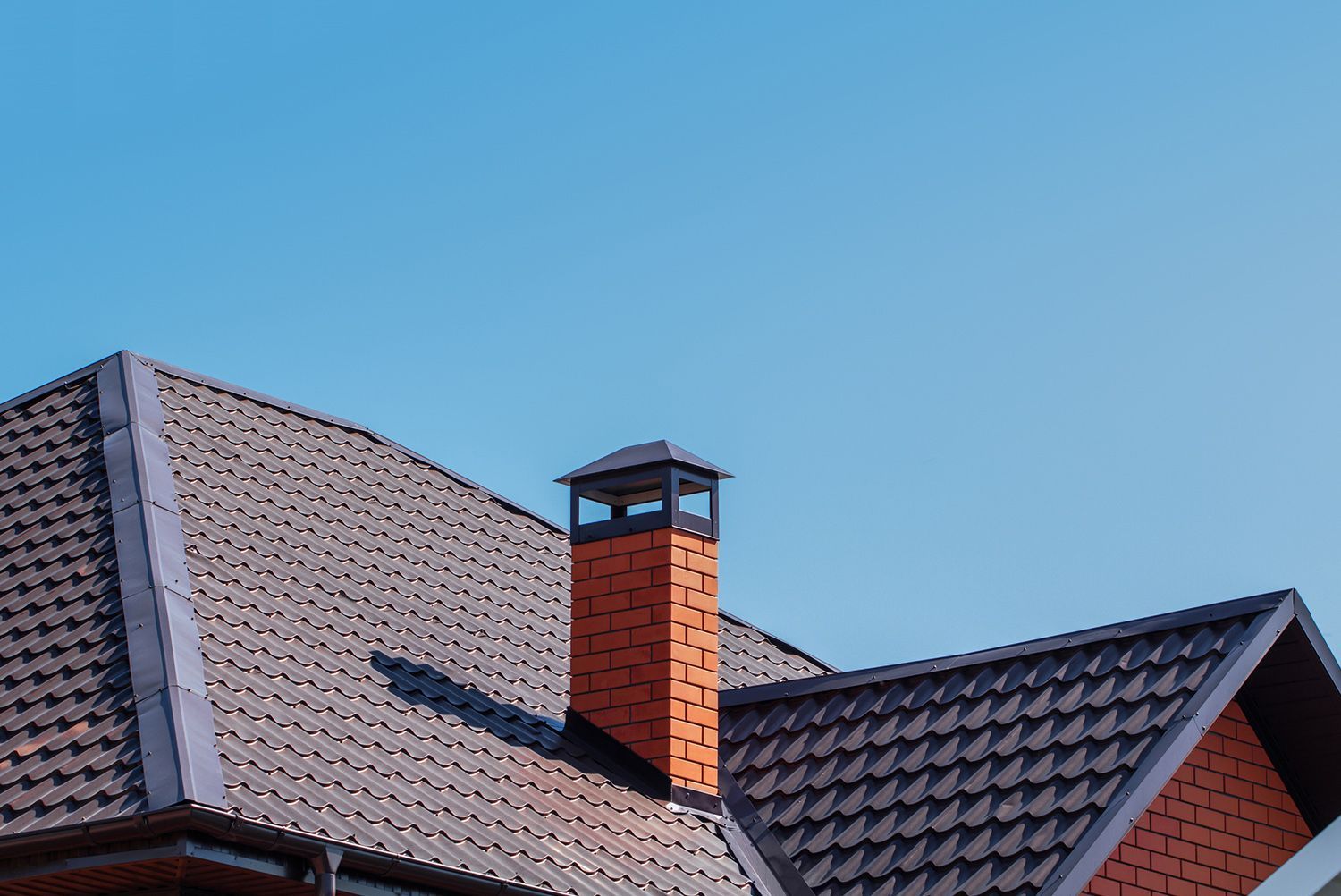 A brick chimney is on the roof of a house.