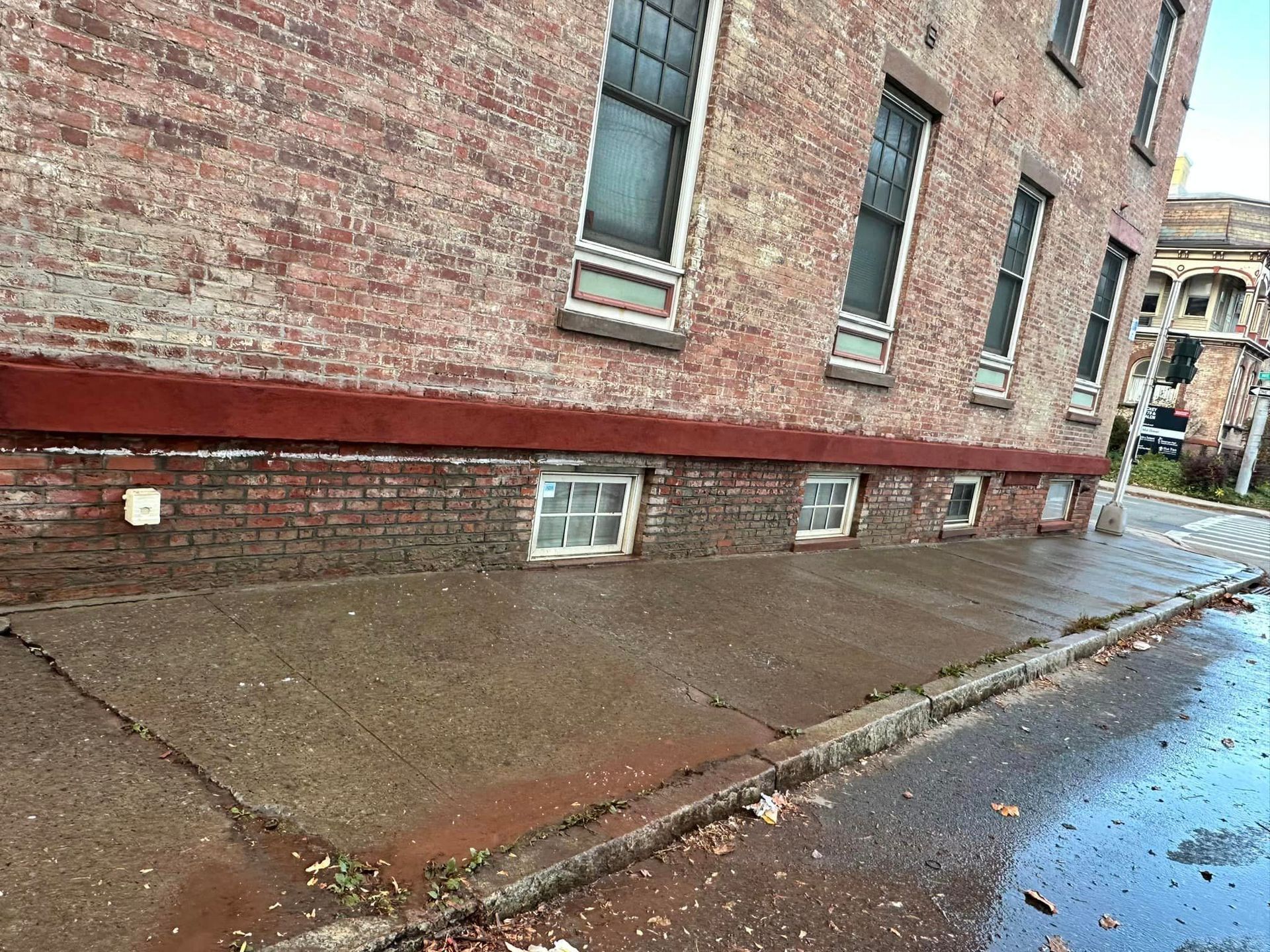 A brick building with a concrete sidewalk in front of it.