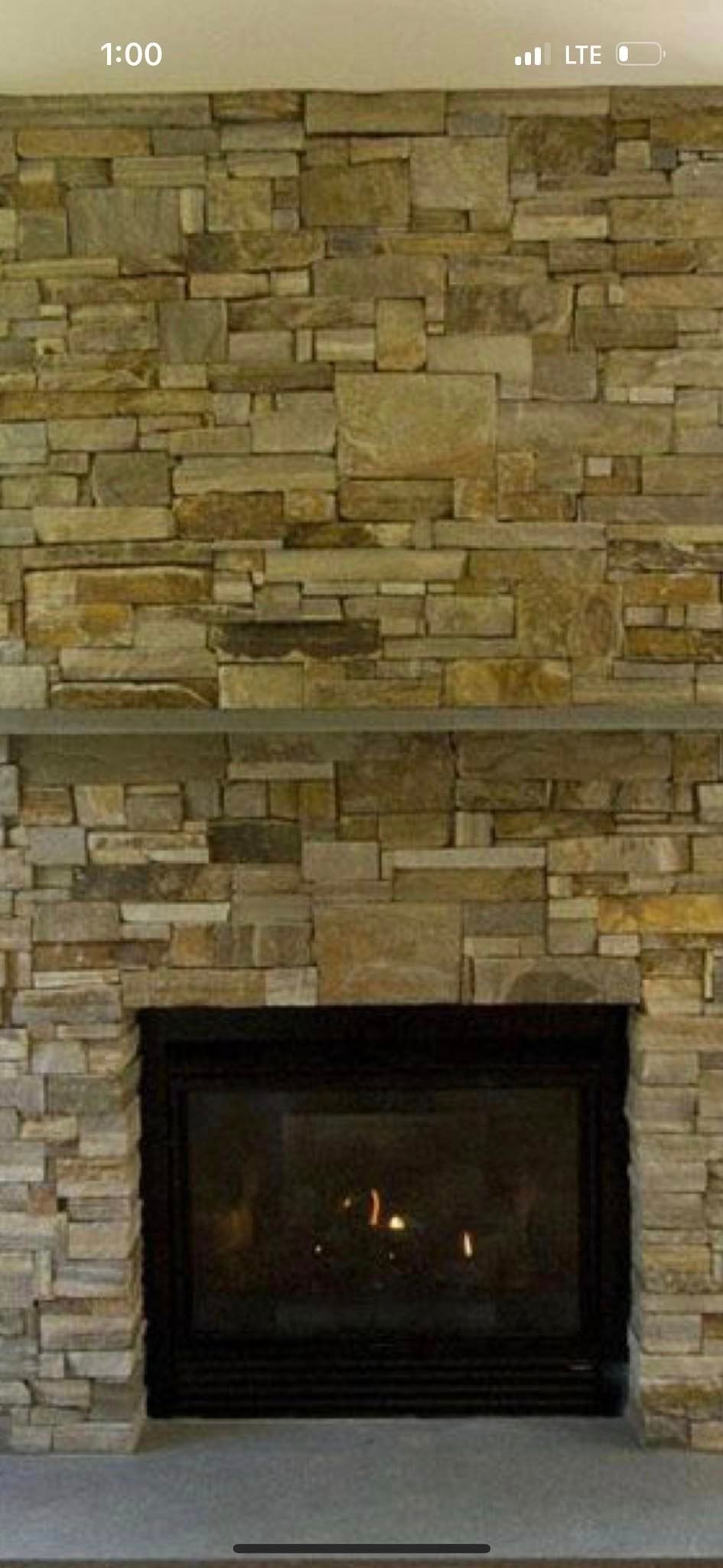 There is a fireplace in the middle of a stone wall.