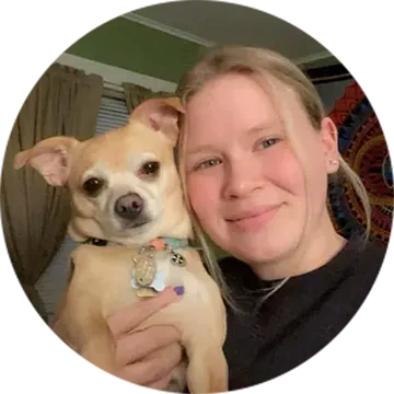 Woman holding a small tan dog, both facing the camera indoors.
