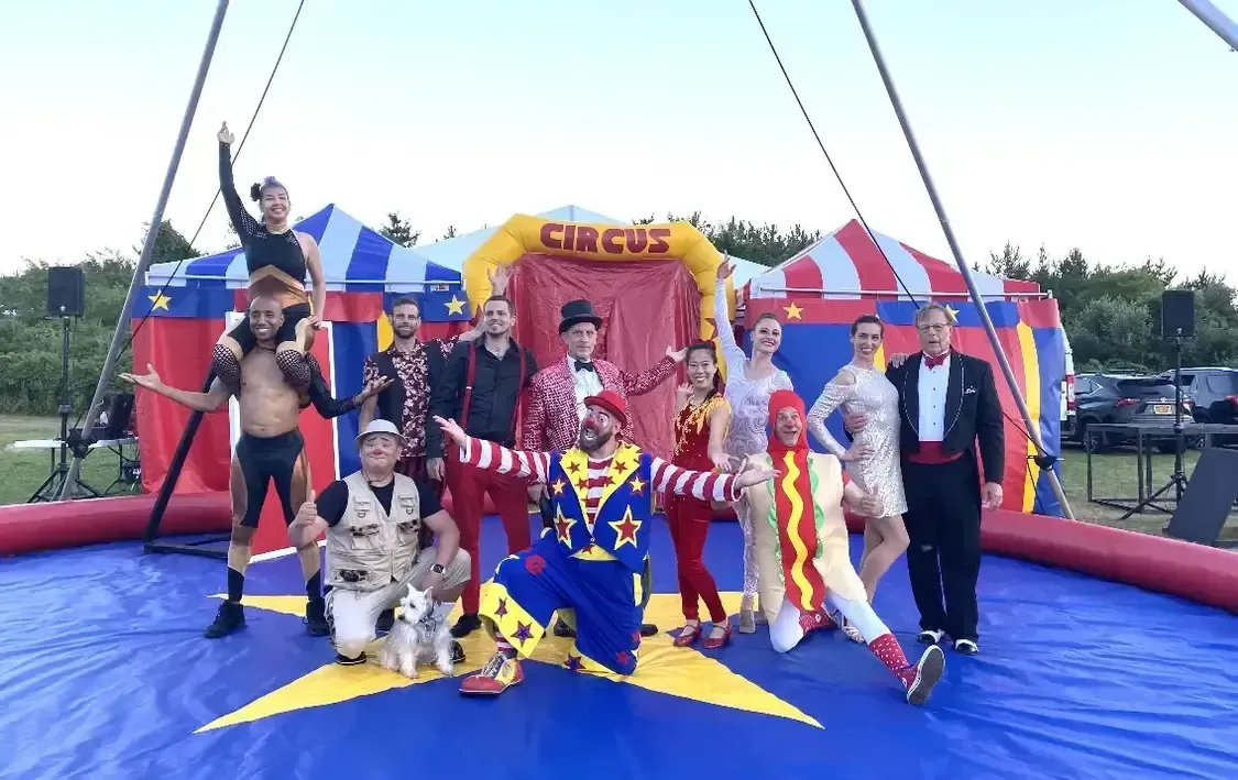 A group of people are posing for a picture in front of a circus tent.
