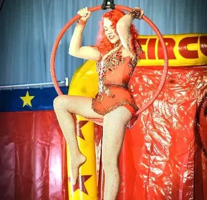 A woman is performing aerial acrobatics in front of a sign that says circus
