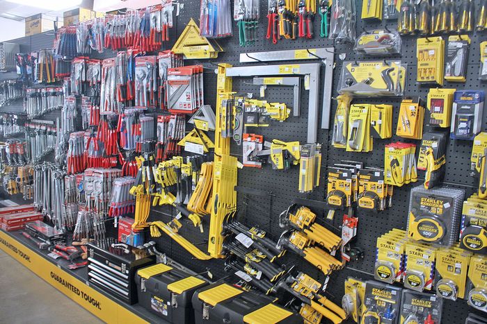 Hardware store aisle with yellow-and-black tools and accessories displayed on shelves and hooks