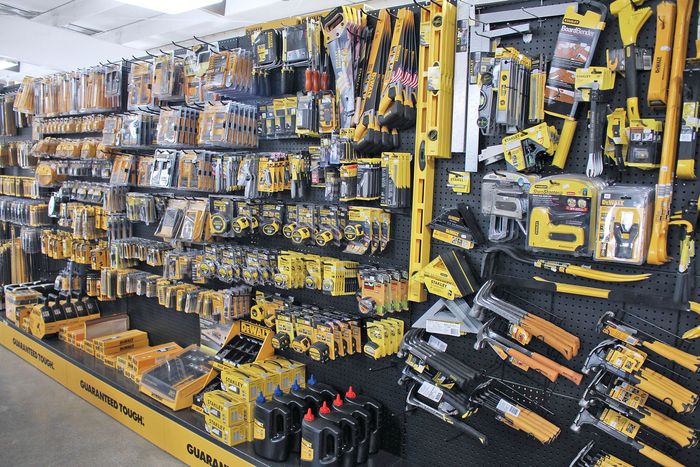 Hardware store aisle filled with yellow-and-black hand tools and tool sets on wall displays
