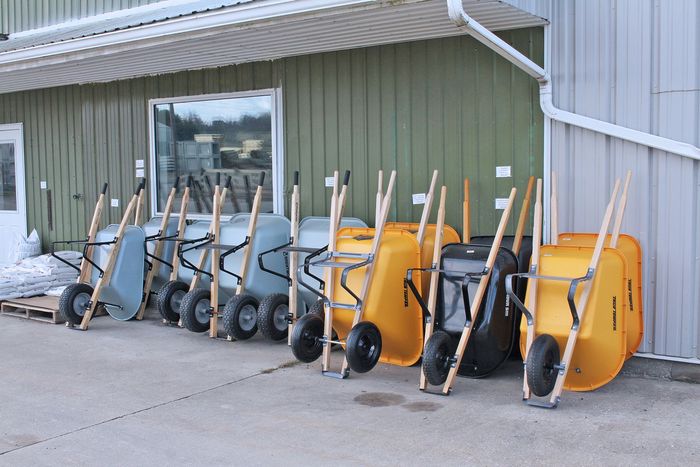 Row of wheeled snow shovels and bins beside a building wall