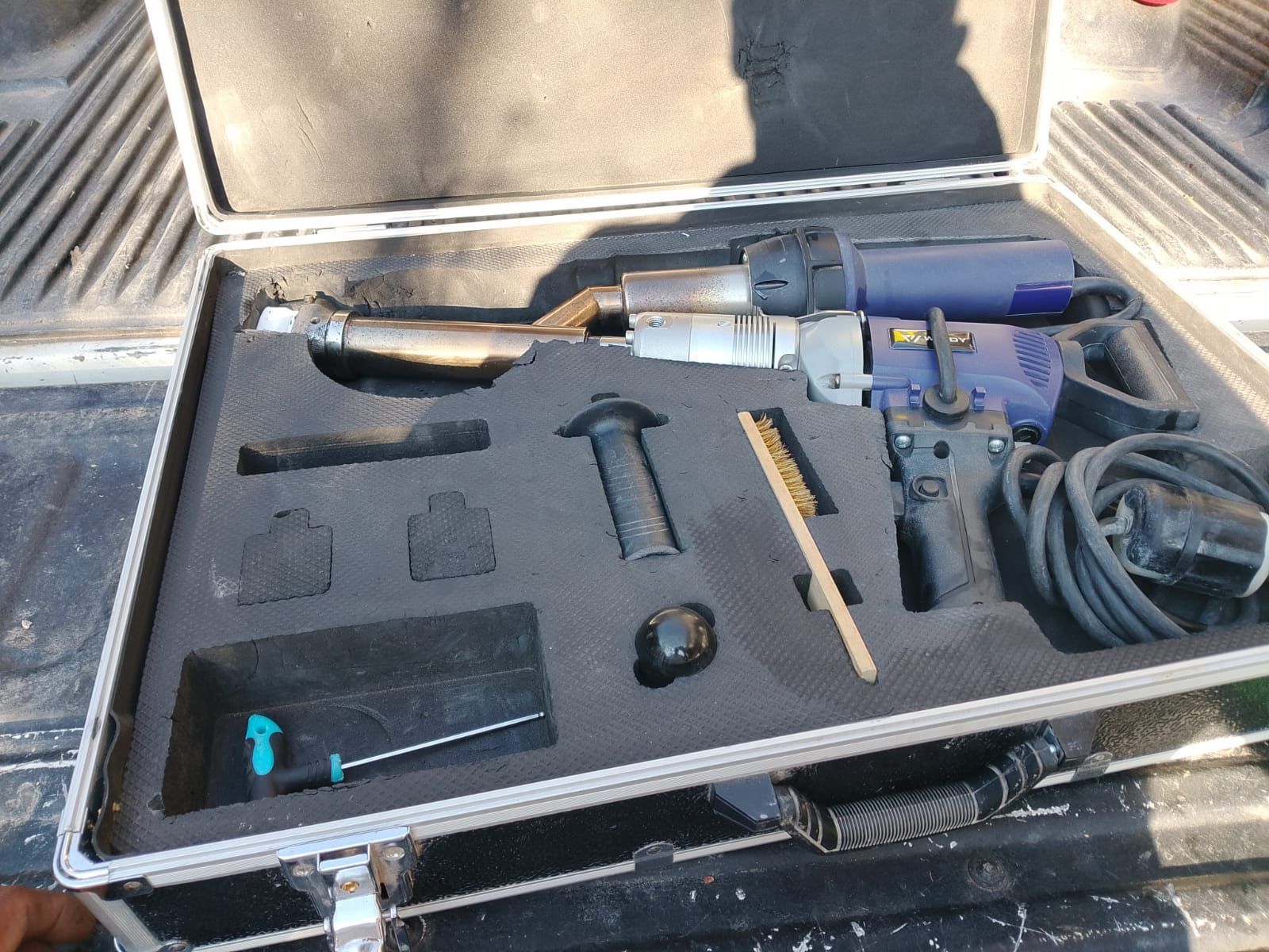 A tool case with a blue and silver plastic welding gun, and accessories arranged inside.