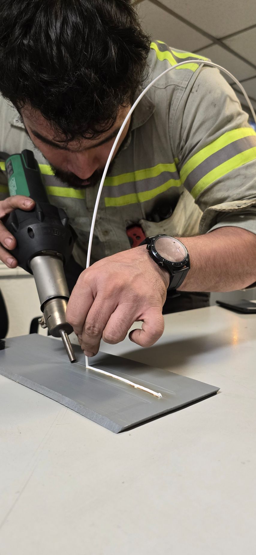 Person uses a heat gun to weld a white material to a gray surface.