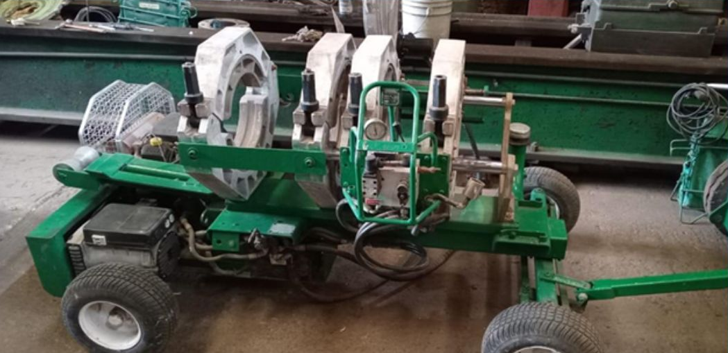 Green industrial pipe fusion machine with wheels.