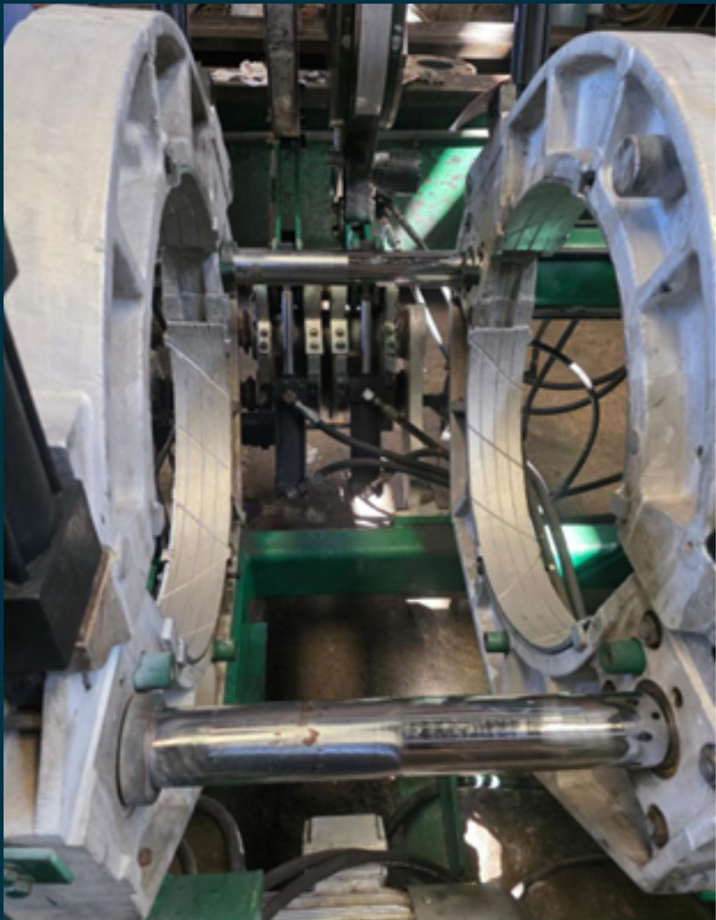 Machine with large white circular components, silver rods, and green structure.