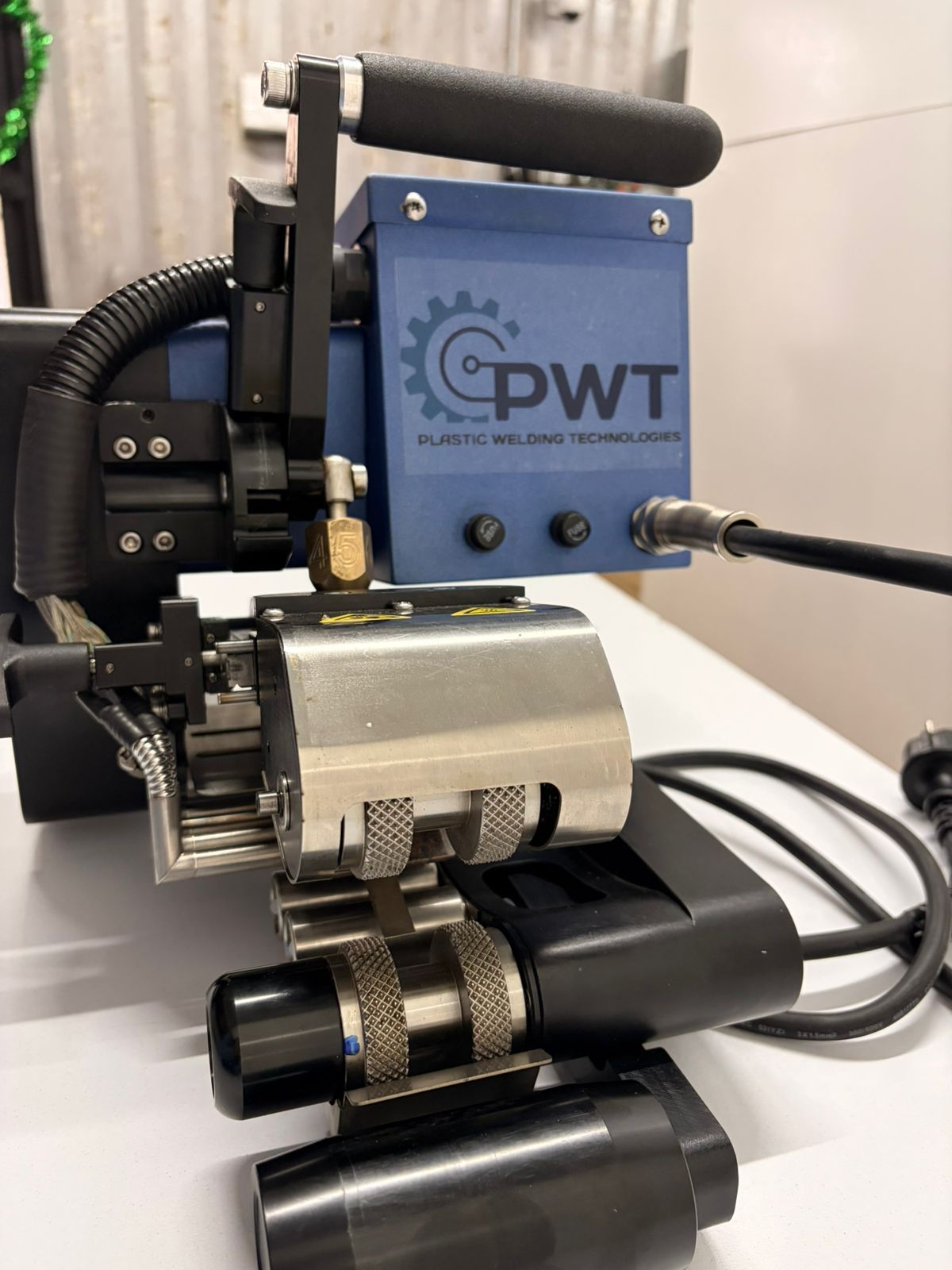 Compact blue-and-black CWT device with rollers and cables on a white surface