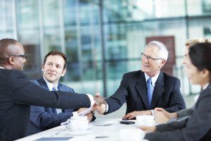 Two formally dressed men shake hands