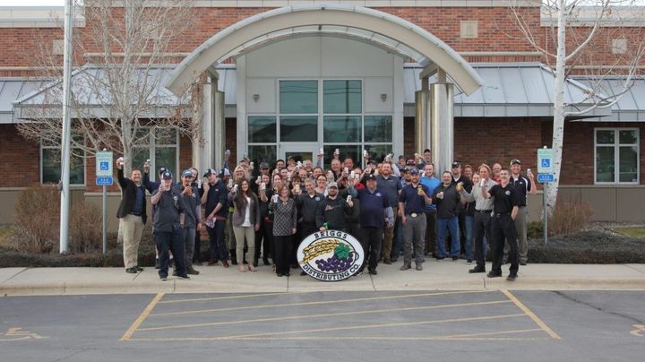 Large group posing outside a brick building entrance, with a uniformed officer at the left.