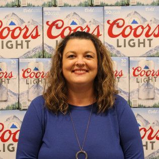 Woman smiling in a blue top in front of a Coors Light backdrop