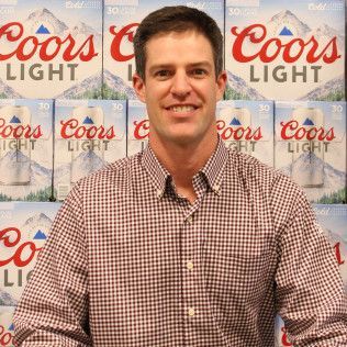 Man smiling in a checkered shirt in front of a Coors Light backdrop
