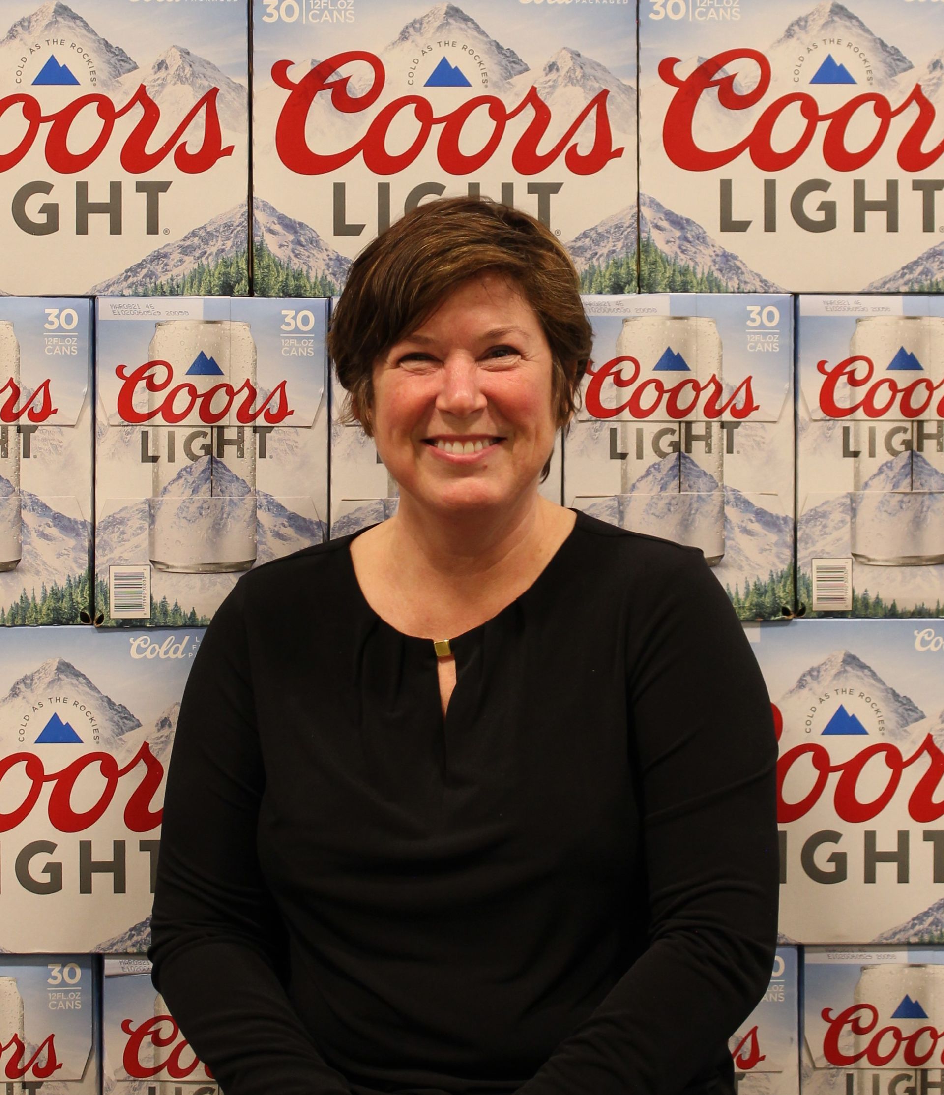 Woman smiling in front of a Coors Light display wall