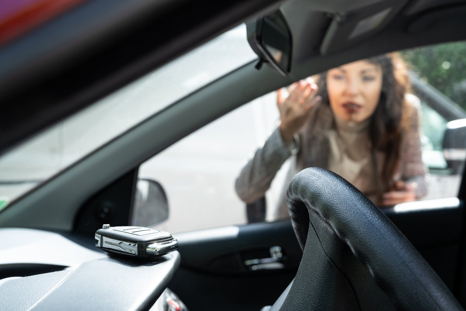 A woman is sitting in a car looking out the window.
