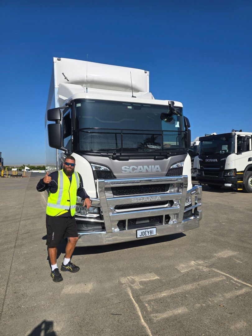 Man in safety vest thumbs up, standing in front of a Scania truck on a sunny day — Go With Joe REMOVALS in Zilzie, QLD