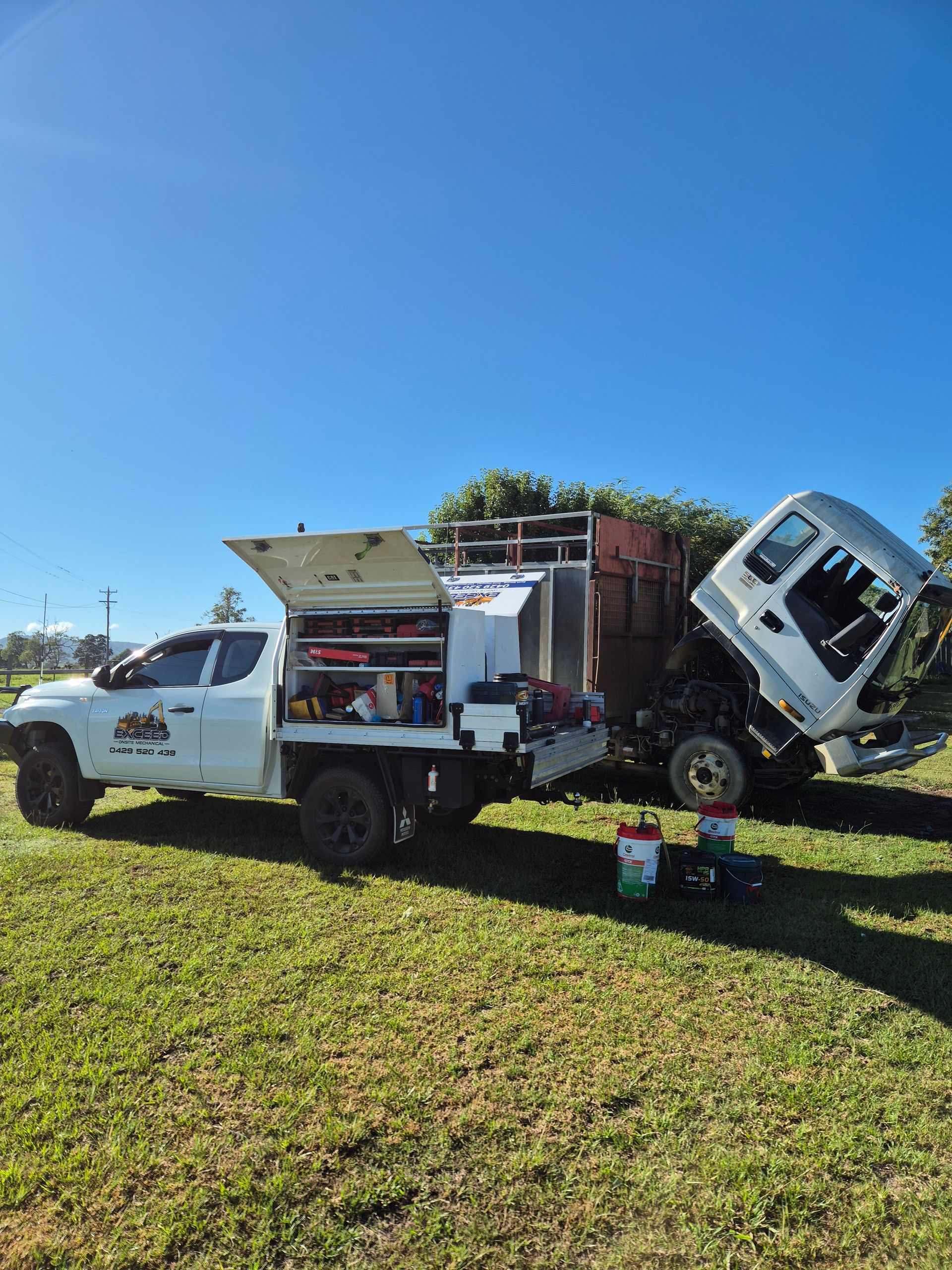 A white service truck with an open tool cabinet parked next to a large commercial truck — Exceed Onsite Mechanical in Grafton, NSW