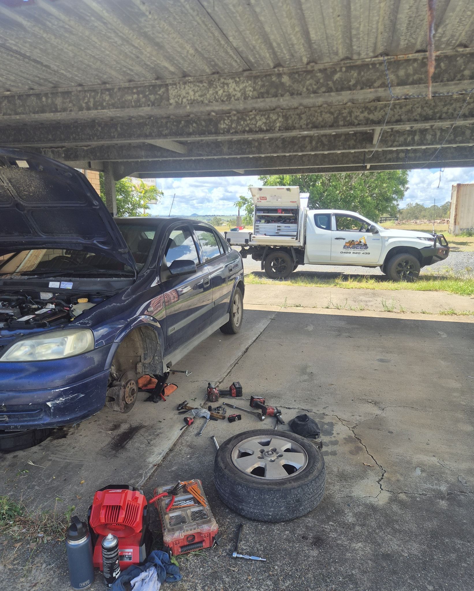 A Blue Car Under a Carport with A White Service Truck — Exceed Onsite Mechanical in Grafton, NSW