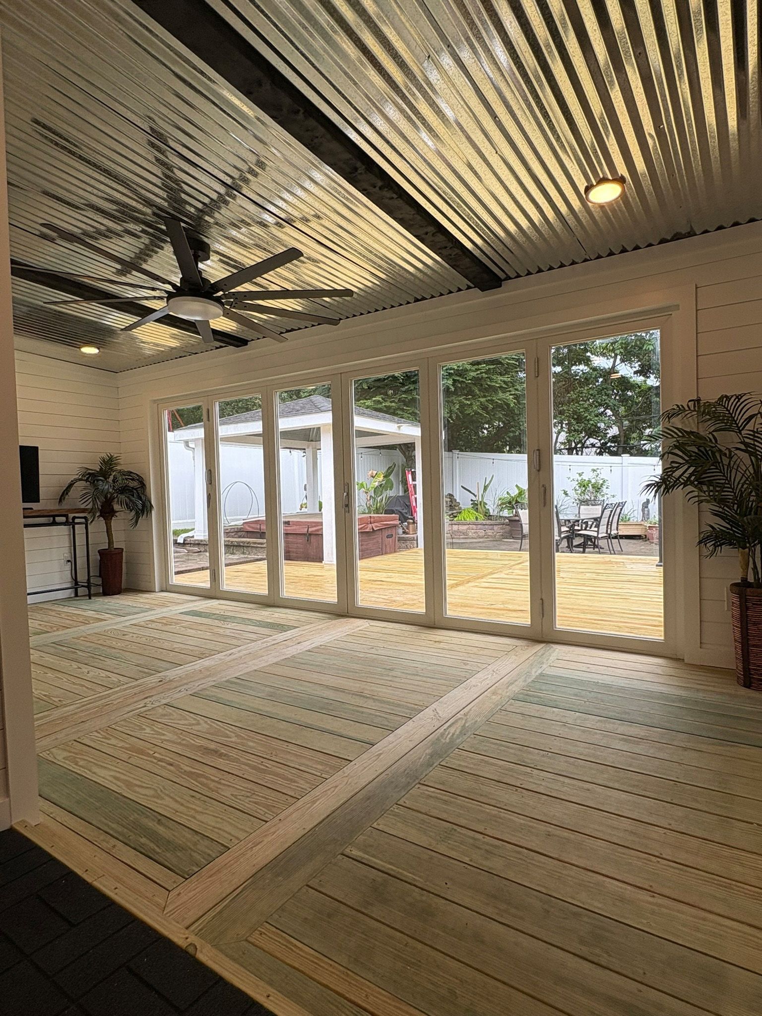 A bright, open room with large glass doors. Striped rug, corrugated metal ceiling, outdoor view.