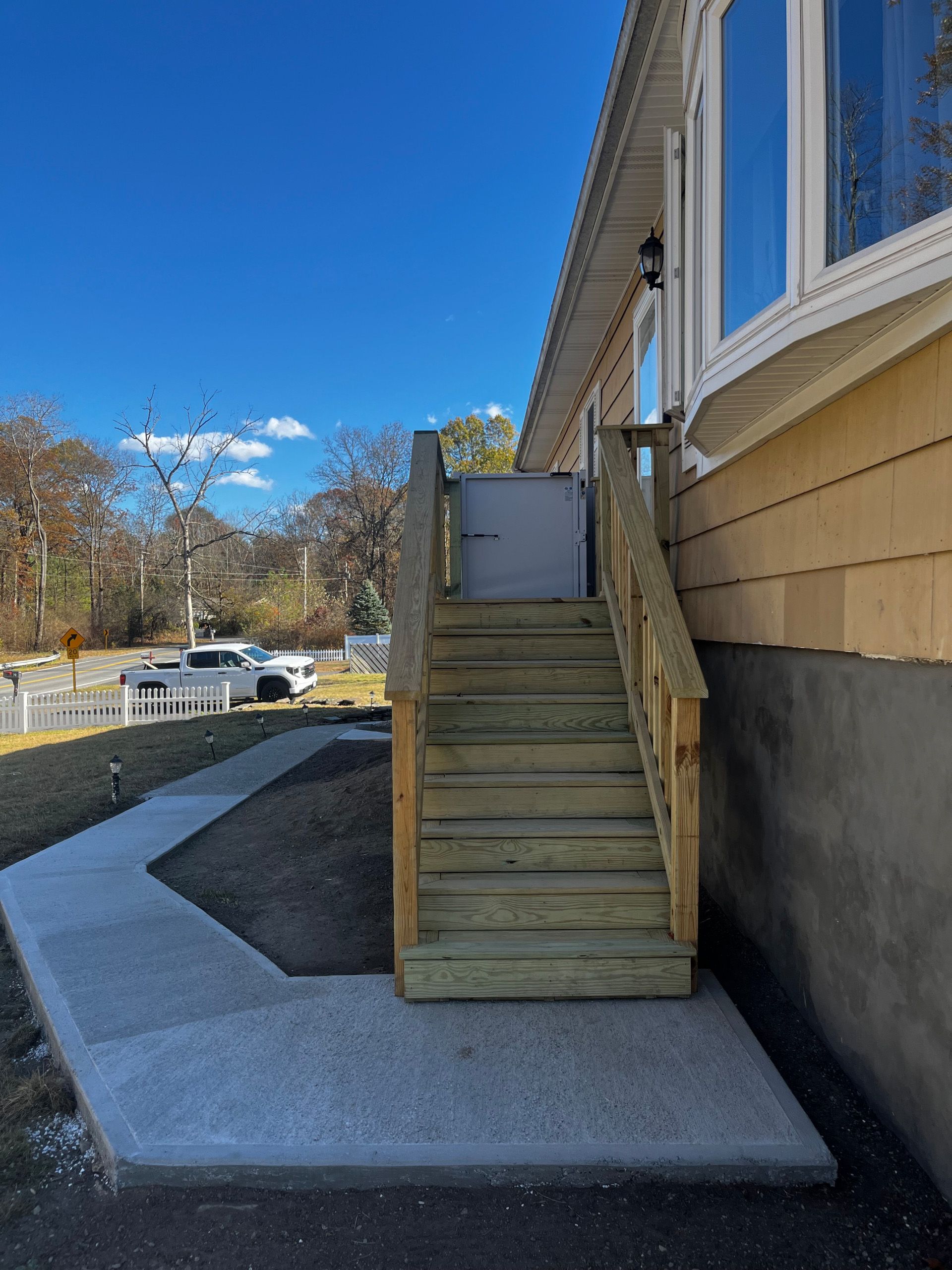 Exterior steps with handrails lead up to a building, beside a paved ramp.