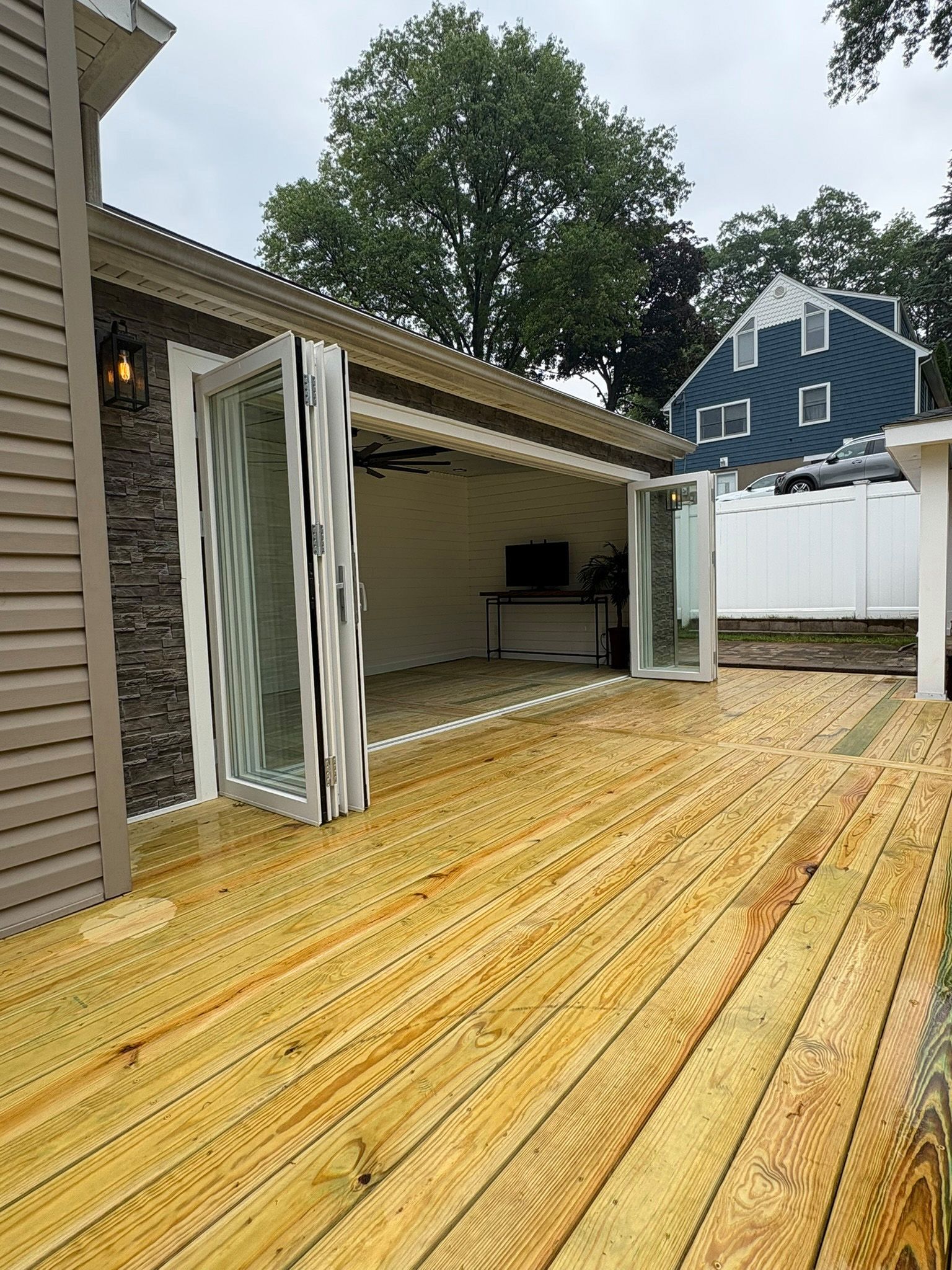 Newly built wooden deck with open glass doors leading into a room, exterior of a house.
