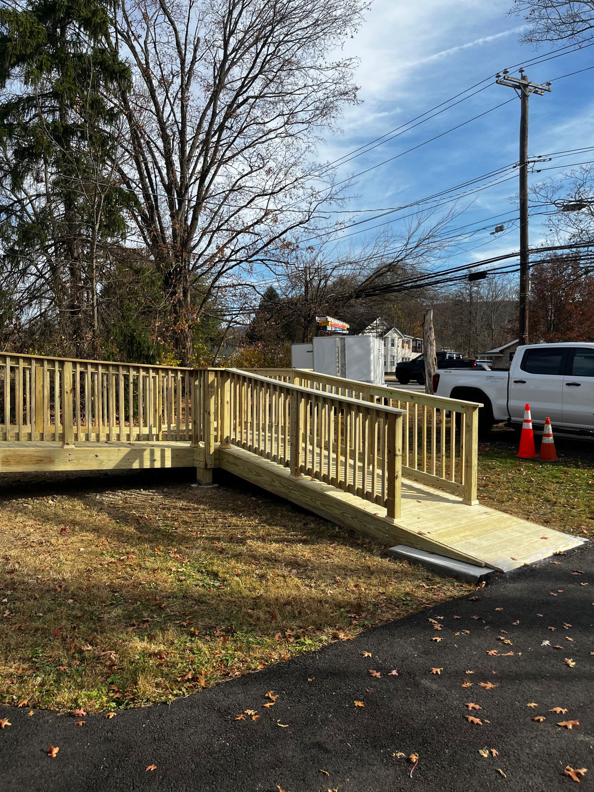 Wooden ramp with railings for accessibility, leading up to a building, outdoors on a sunny day.