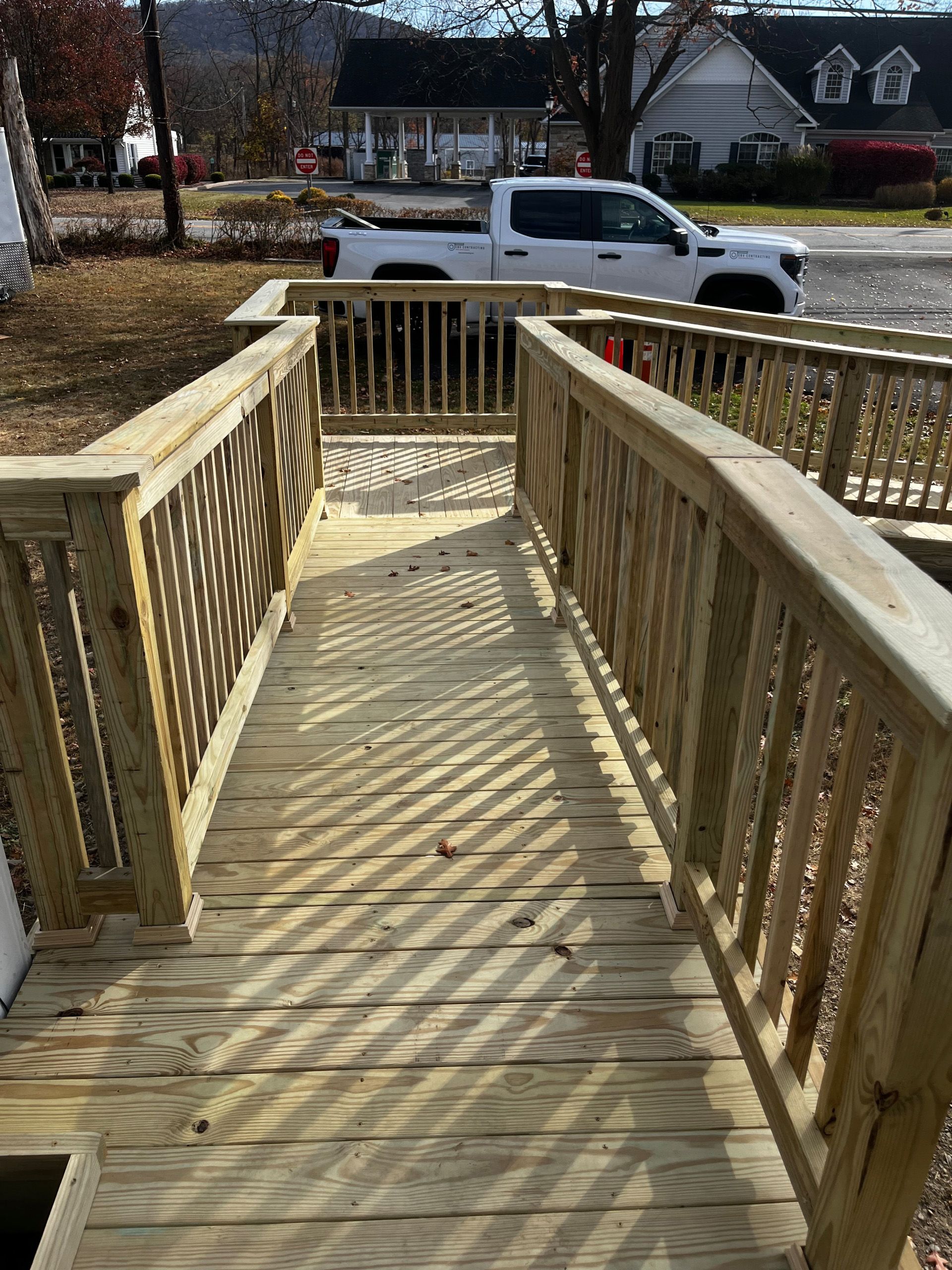 Wooden ramp with railings, leading to a door, in a residential setting.