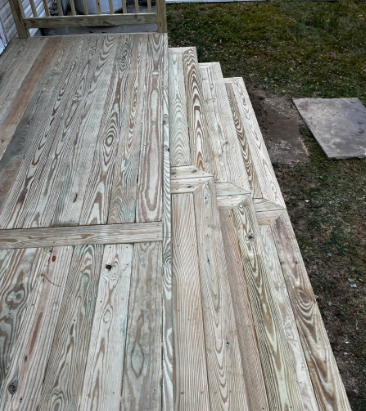 Weathered wooden deck and steps leading down to grassy yard.