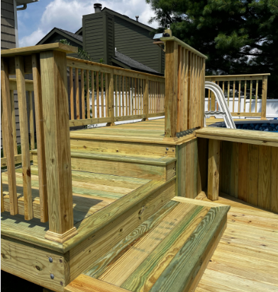 Wooden deck with steps and railings, near an above-ground pool. Sunlight highlights the wood's natural tones.