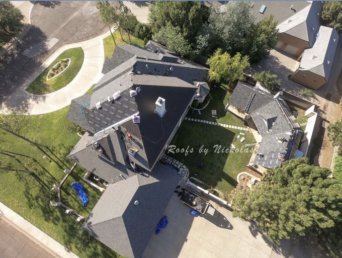 Aerial view of a large residential home with new asphalt shingle roof