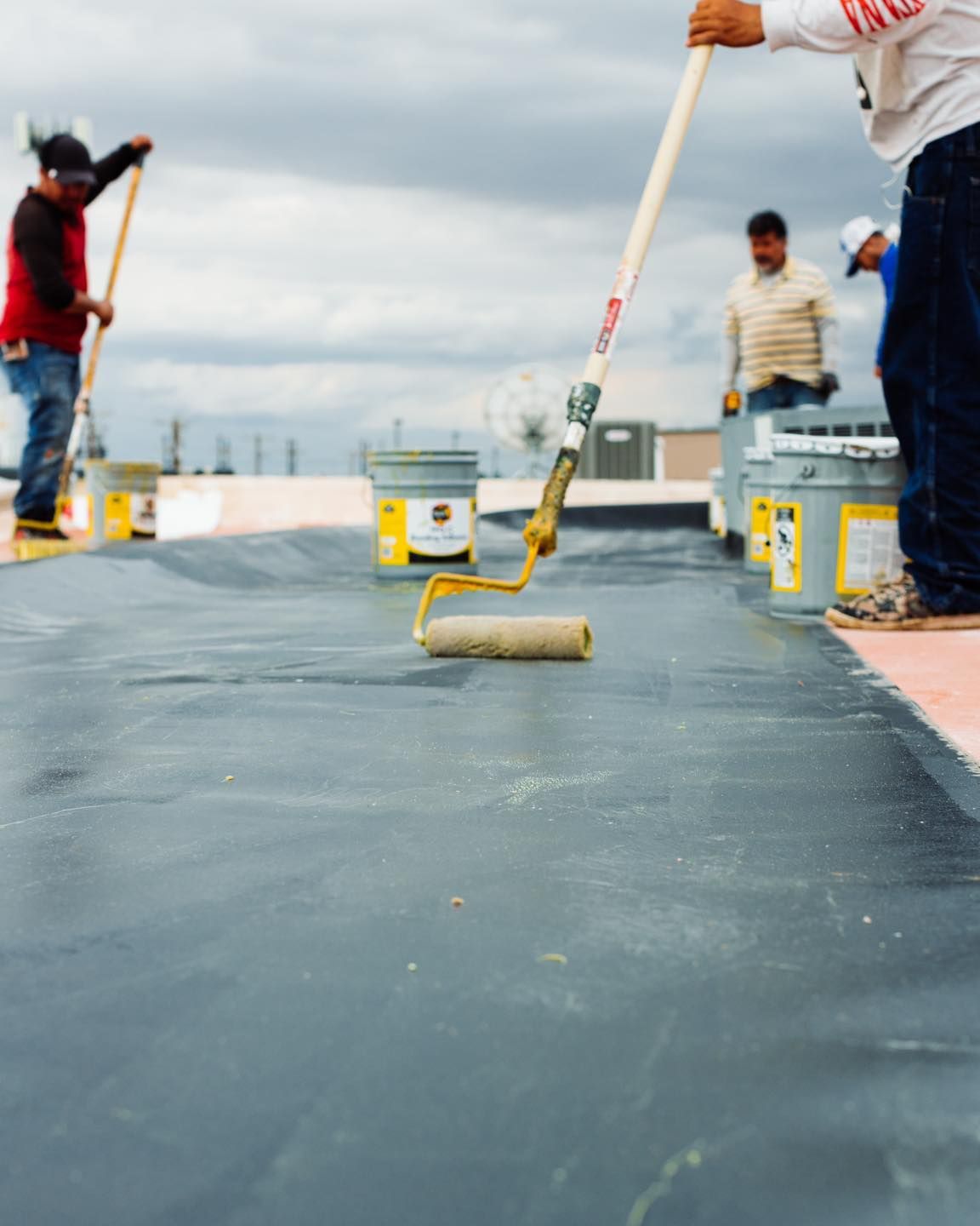 Close-up of roller applying waterproof coating on flat commercial roof